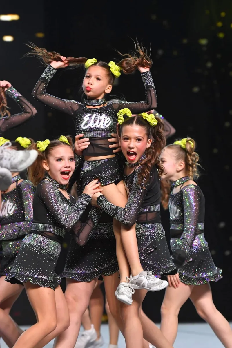 Elite Cheer flyer held in a stunt by teammates on the competition floor